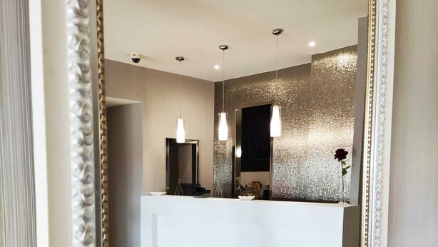 Une salle de bain moderne avec un grand miroir, un plan de toilette blanc et un vase décoratif contenant des roses rouges.