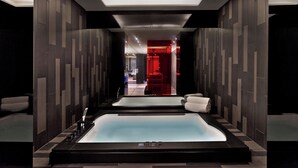 A modern spa area with two large tubs, a reception area in the background, and a sleek, contemporary design. - W London (London)