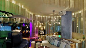 A modern lounge area with a bar, seating, and a large column. - W London (London)