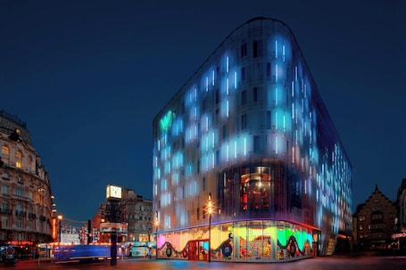A modern building with a glass facade and illuminated windows at night.