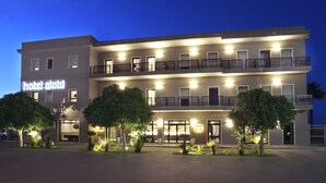 A hotel with a modern facade, multiple balconies, and a well-lit entrance.