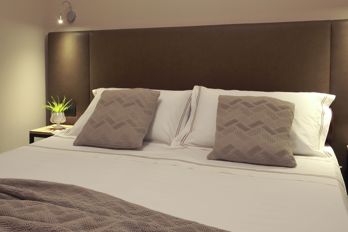 A neatly made bed with a brown headboard, white pillows, and a brown blanket.