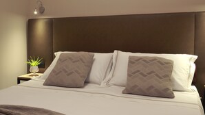 A neatly made bed with a brown headboard, white pillows, and a brown blanket.