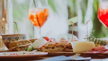 Una mesa con diferentes alimentos, incluyendo sándwiches, queso y una copa de vino tinto.