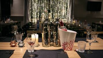 Un ambiente de restaurante con una mesa lista para cenar, con copas de vino, una vela y botellas decorativas.