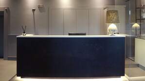 A modern reception desk with a dark surface, a lamp, and a small table with a bottle and stoppers.