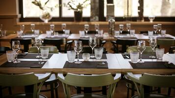 Un restaurante con varias mesas dispuestas para comer, cada una con sillas y vasos transparentes.