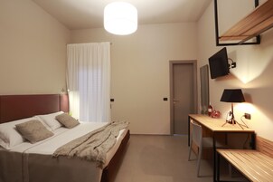 Una camera da letto con un letto, un comodino, una lampada e una scrivania con una sedia.