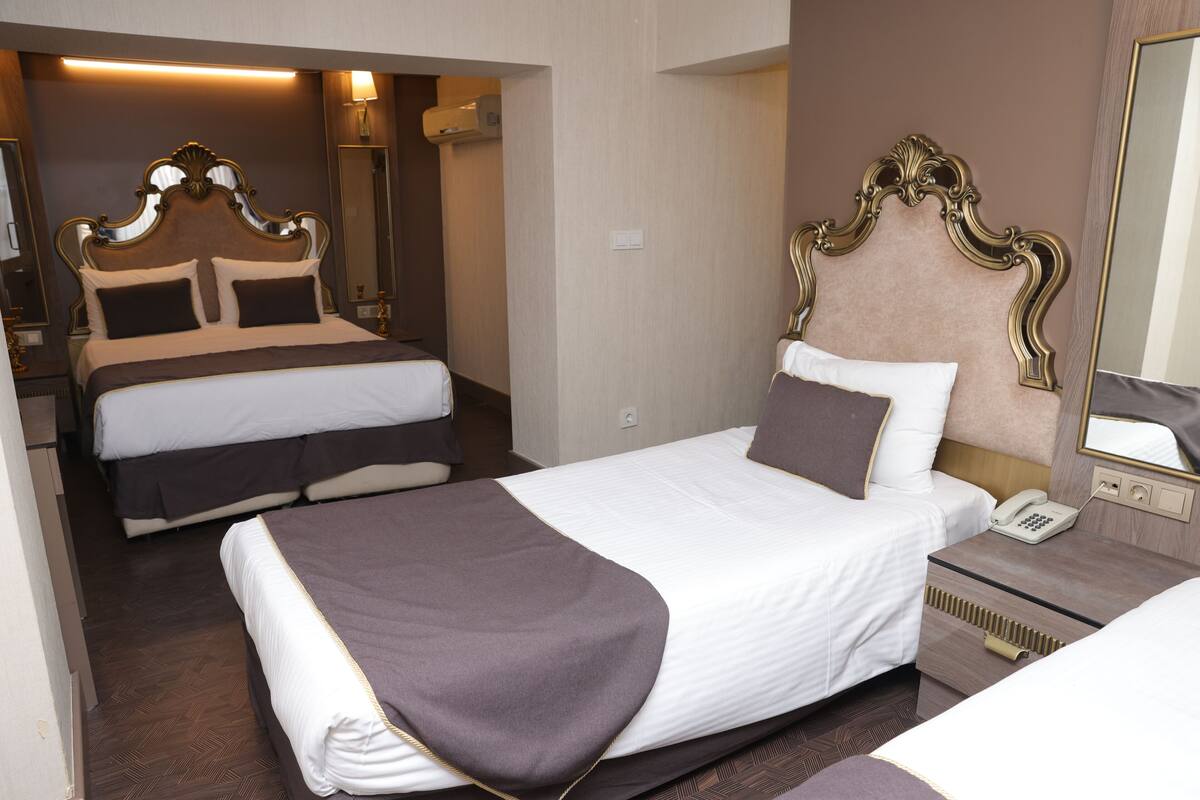 Une chambre d’hôtel avec deux lits, une table de chevet avec un téléphone et un miroir.