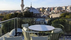 A rooftop terrace with a round table and chairs, offering a view of a cityscape including a mosque and a minaret. - Dara Old City Hotel (Istanbul)