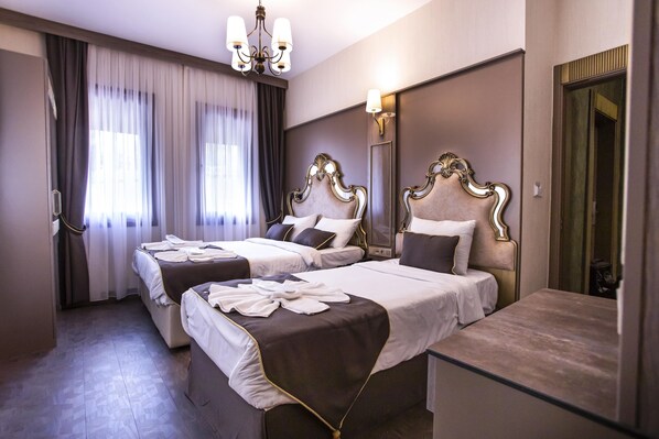 Ett hotellrum med två sängar, en stor spegel och en kristallkrona.