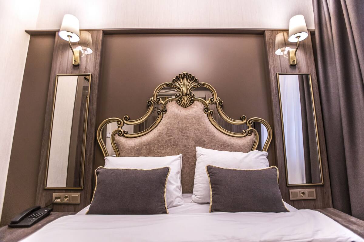 Une chambre d’hôtel avec un grand lit, deux lampes de chevet, un miroir et une télécommande sur la table de chevet.