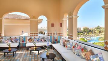 Eine Lounge mit Sofas, Tischen und Blick auf Pool und Gebäude.