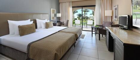 A hotel room with a large bed, a desk, a television, and a view of the outdoors.