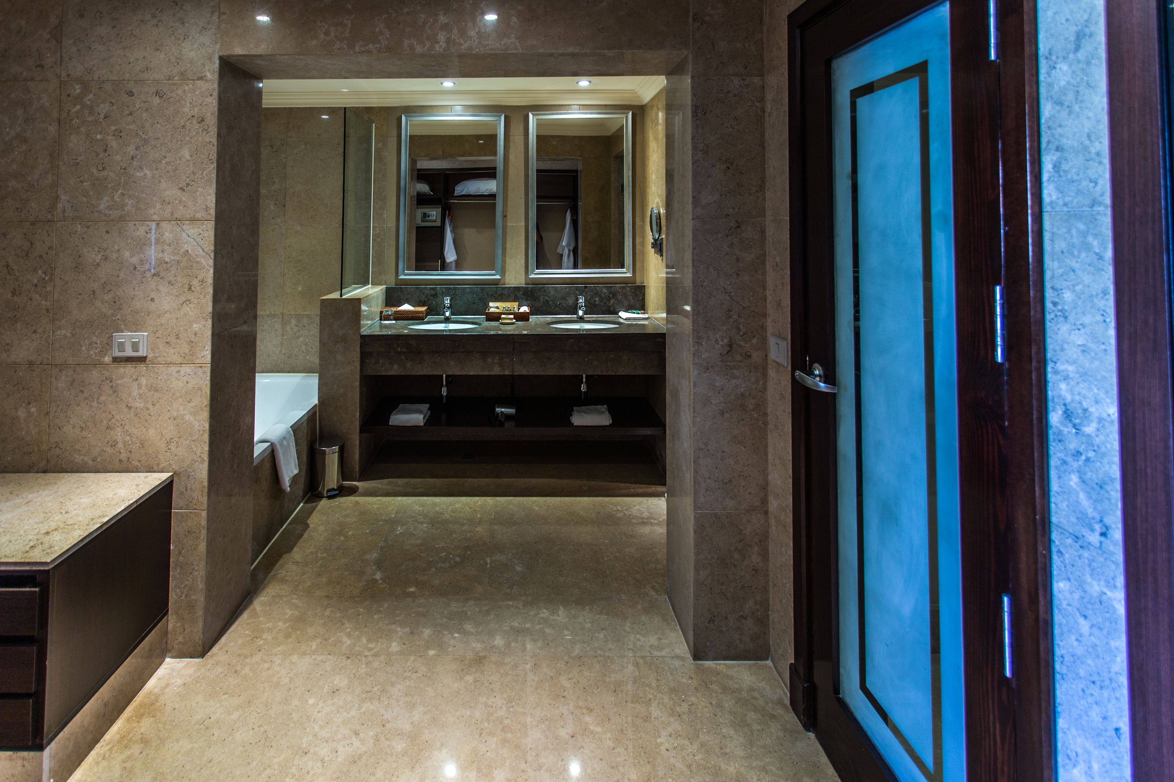 Un baño moderno con dos lavamanos, un espejo grande y una puerta de madera.