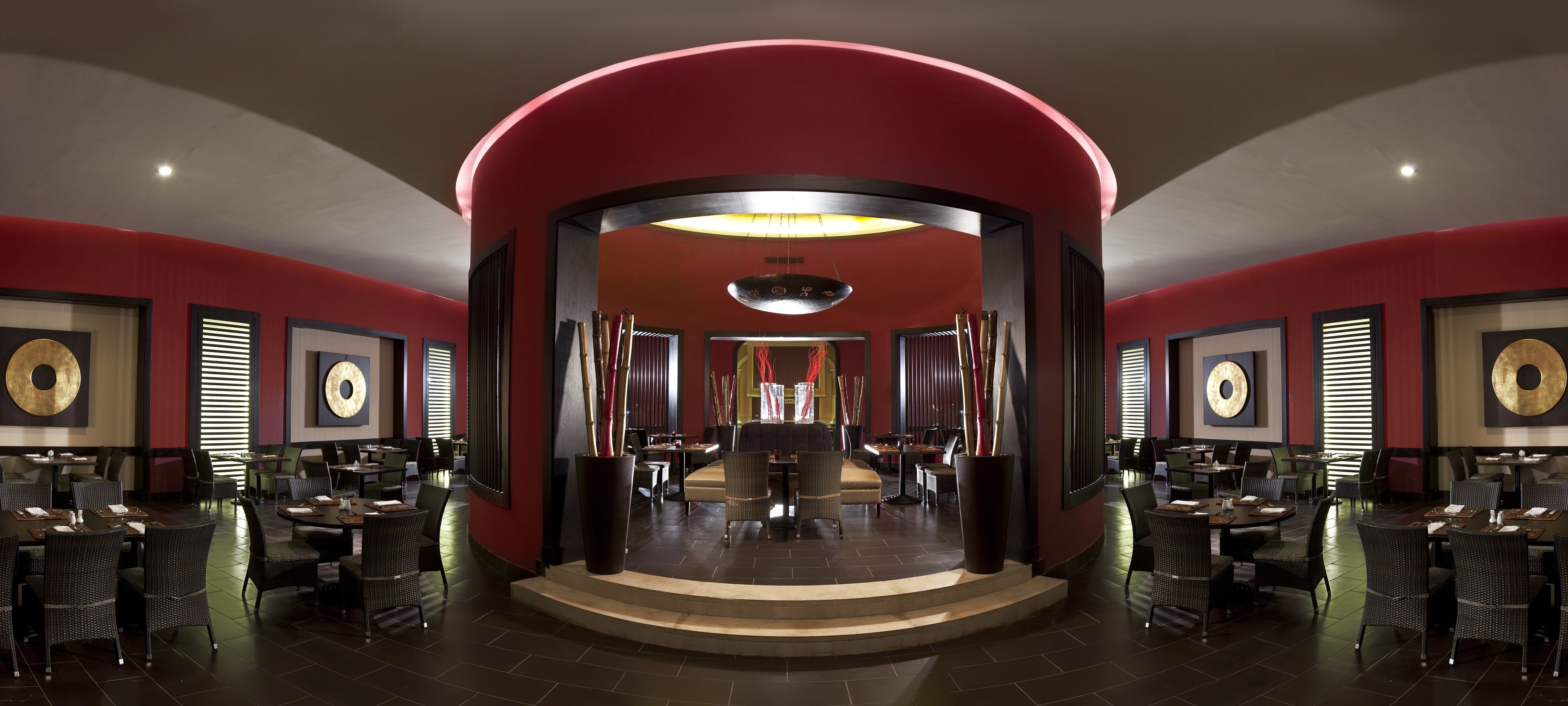 Ein geräumiges Restaurant mit roten Wänden, mehreren Tischen und Stühlen.