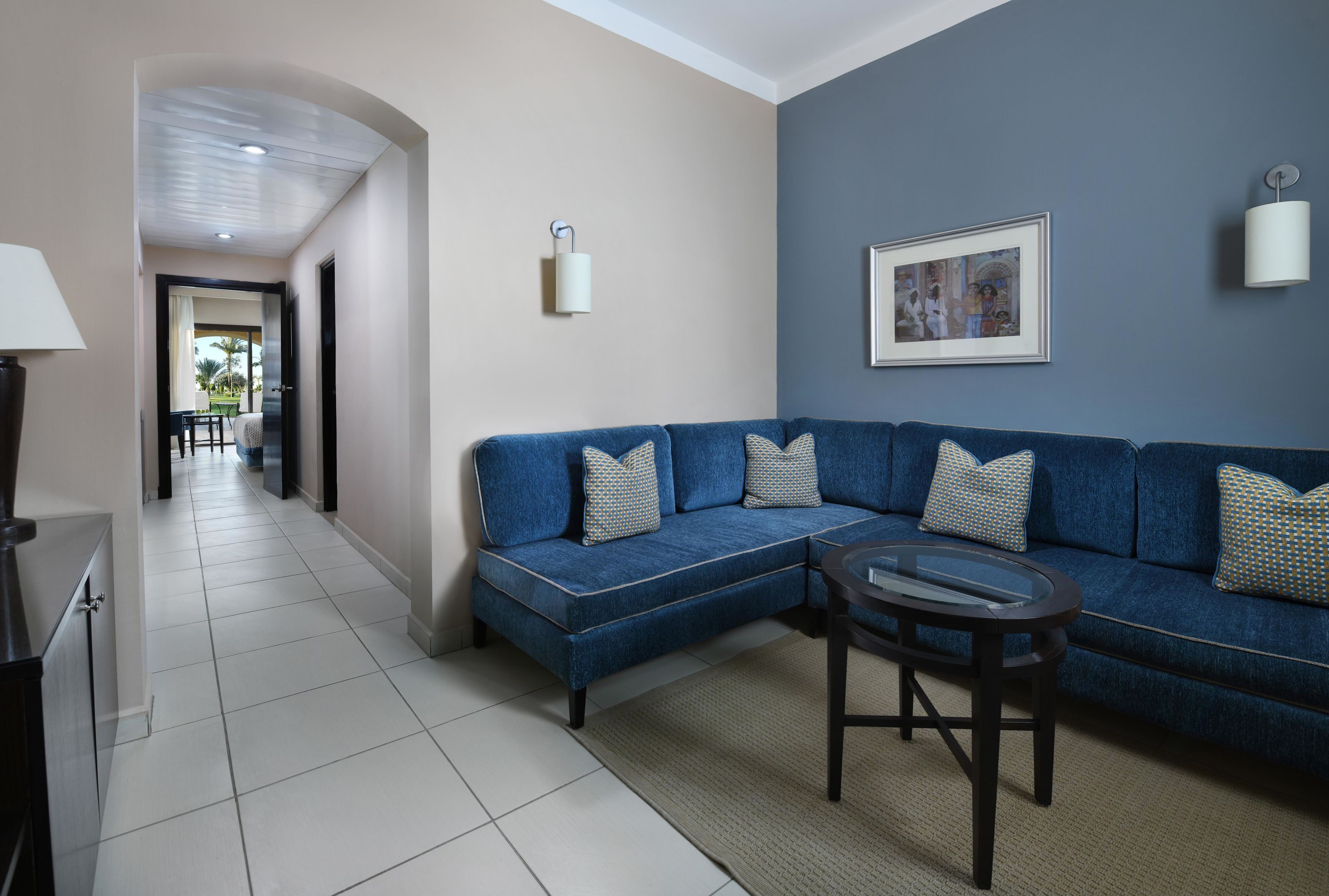 Ein modernes Wohnzimmer mit einem blauen Sofa, einem kleinen runden Tisch und einem gerahmten Bild an der Wand.