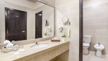 A modern bathroom with a large mirror, a sink, a toilet, and a bidet.