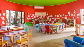 Un'aula dai colori vivaci, con pareti rosse, diversi tavoli e sedie.