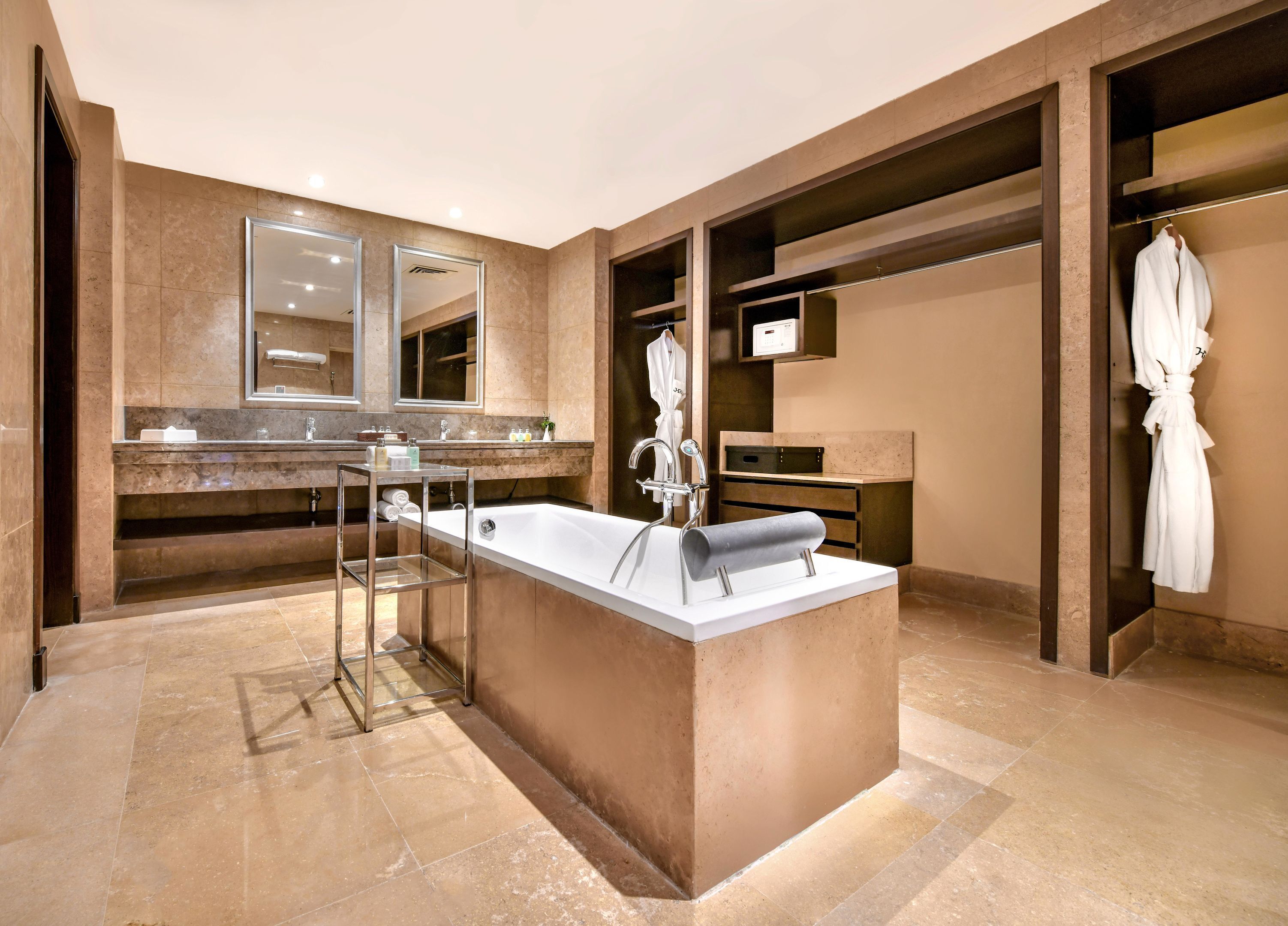 A modern bathroom with a large bathtub, a vanity with a mirror, and a robe hanging on a rack.