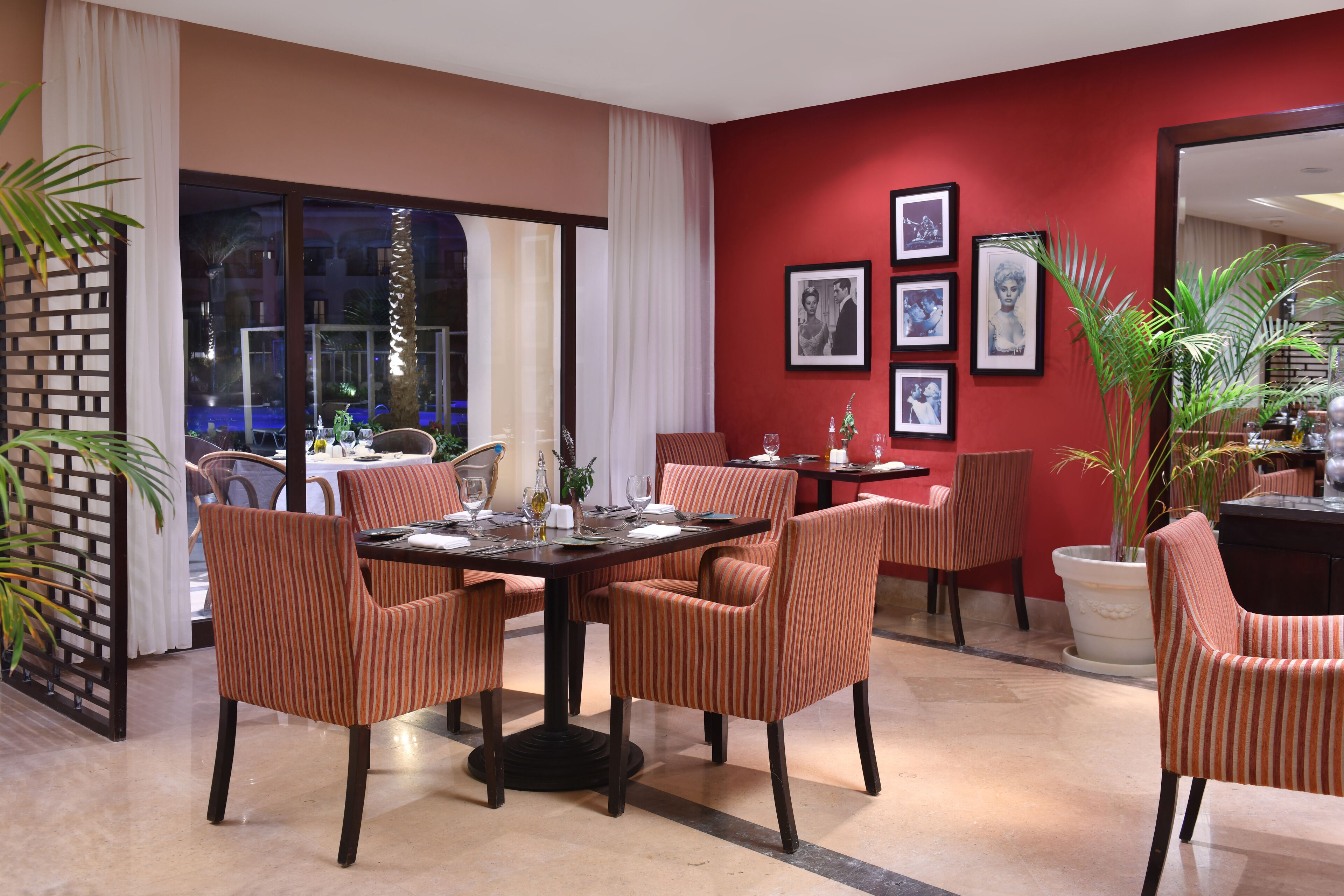 A dining area with striped chairs, a dark table, and framed pictures on the wall.