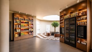 Eine geräumige Lobby mit Holzbögen, die verschiedene Produkte präsentieren, einer zentralen Sitzgruppe und einer großen Topfpflanze.