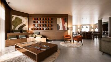 A modern living room with a foosball table, a sofa, and a dining area with chairs and tables.