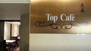 Une enseigne pour le « Top Café », avec une écriture décorative et un logo.