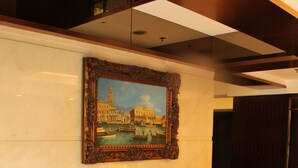 Un hall d’entrée avec deux fauteuils en cuir, une petite table et un tableau encadré représentant un paysage urbain.
