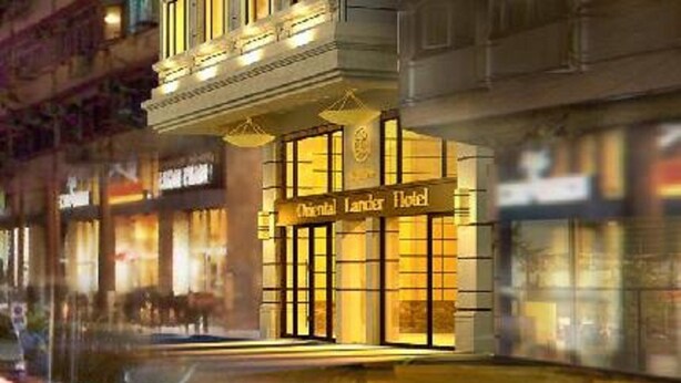 La façade d’un hôtel, sur laquelle on peut lire l’inscription « Oriental Land Hotel ».