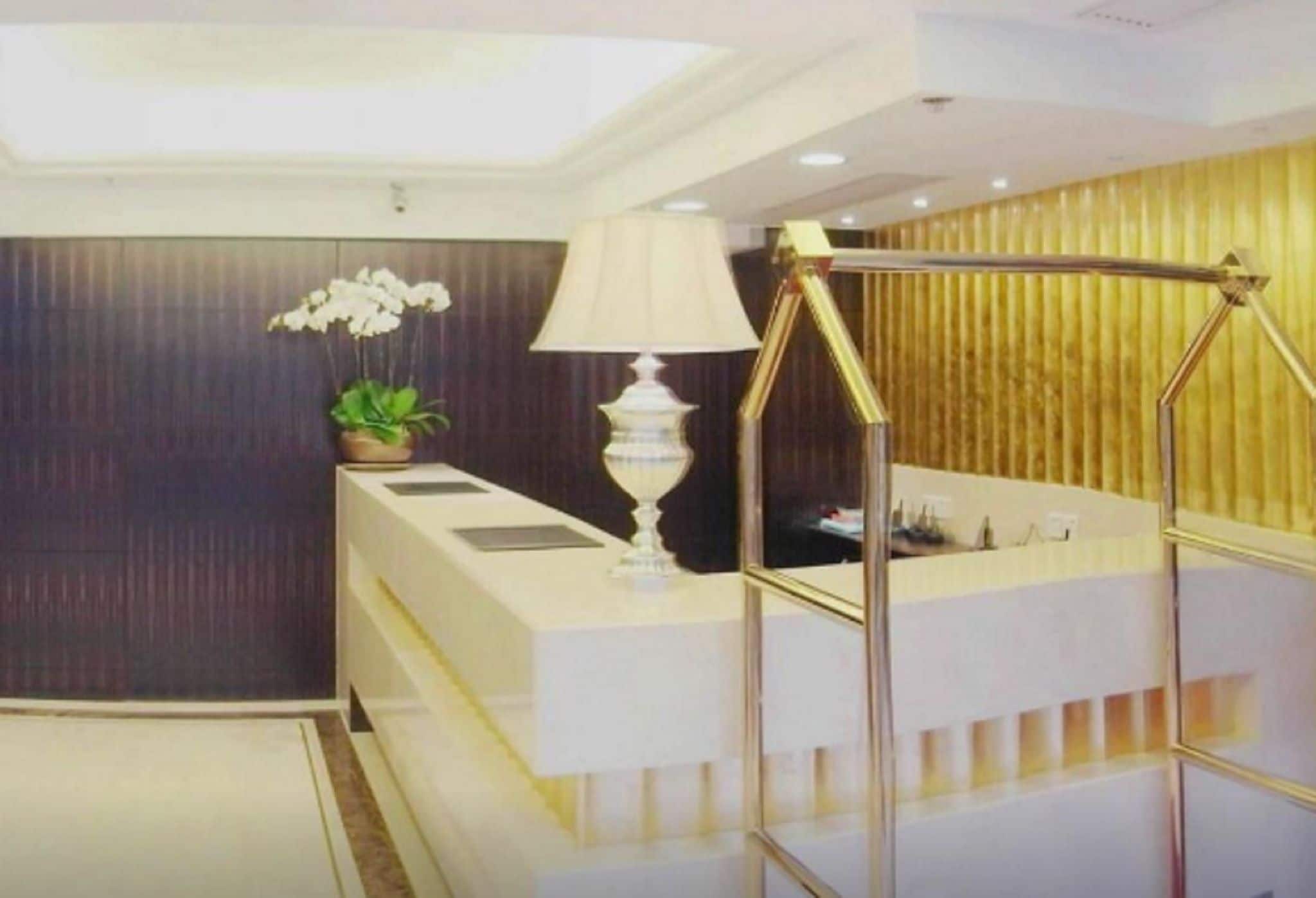 A modern bathroom with a white vanity, a gold-framed mirror, and a potted orchid.