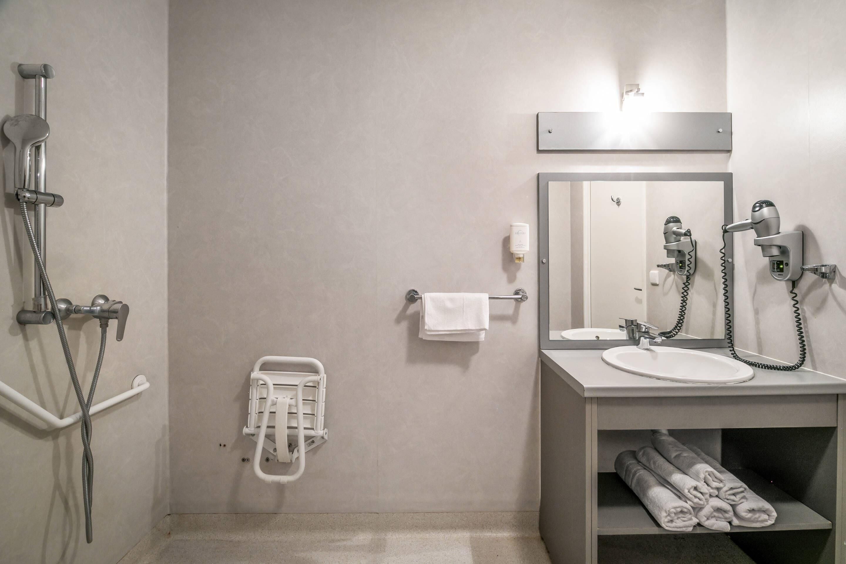 A modern bathroom with a shower, sink, and hairdryer.