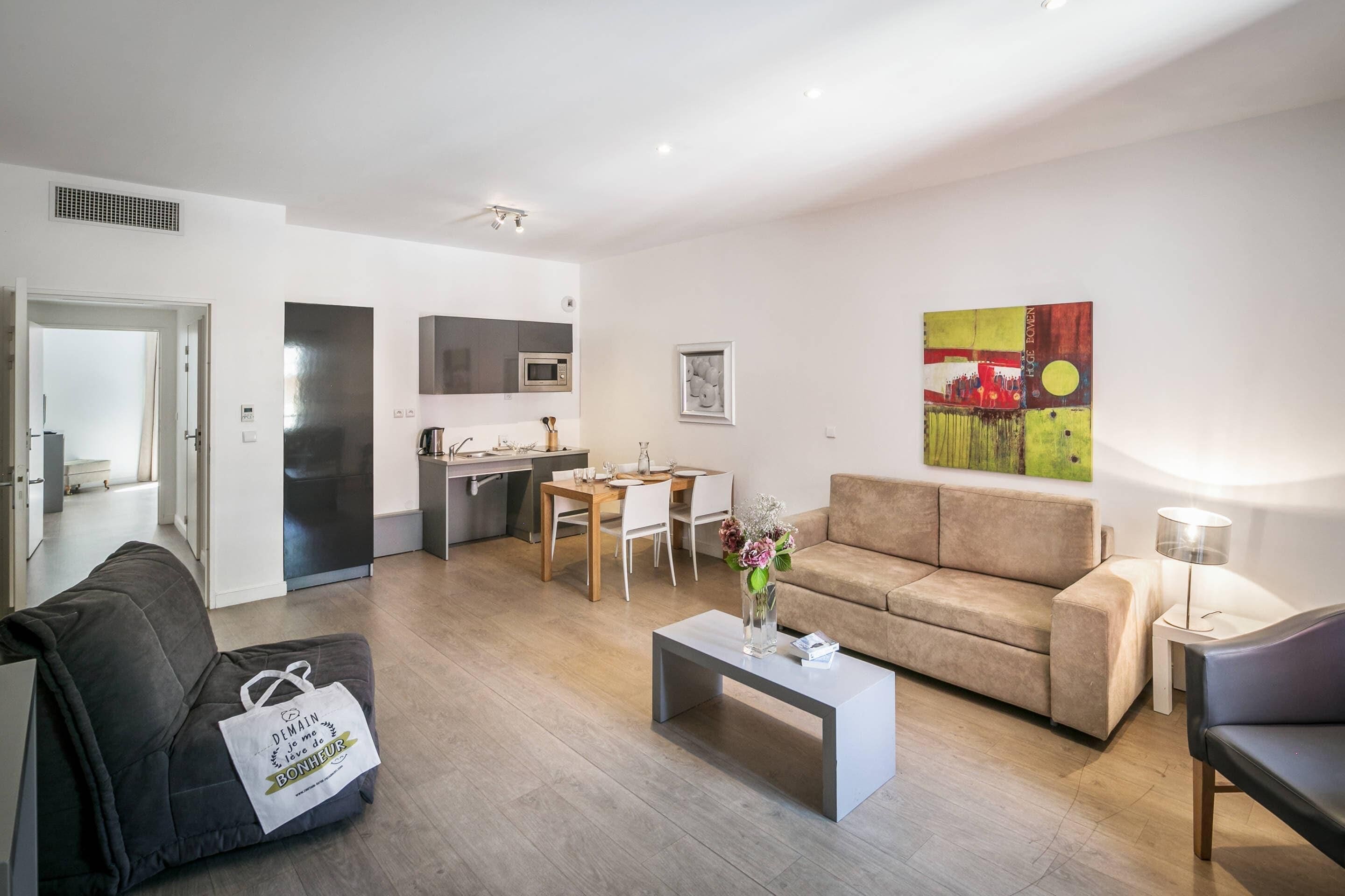 A modern living room with a sofa, coffee table, and a dining area with a table and chairs.