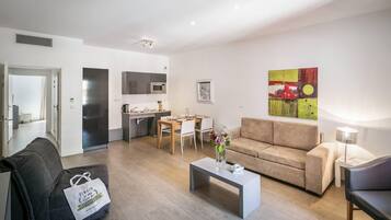 A modern living room with a sofa, coffee table, and a dining area with a table and chairs.