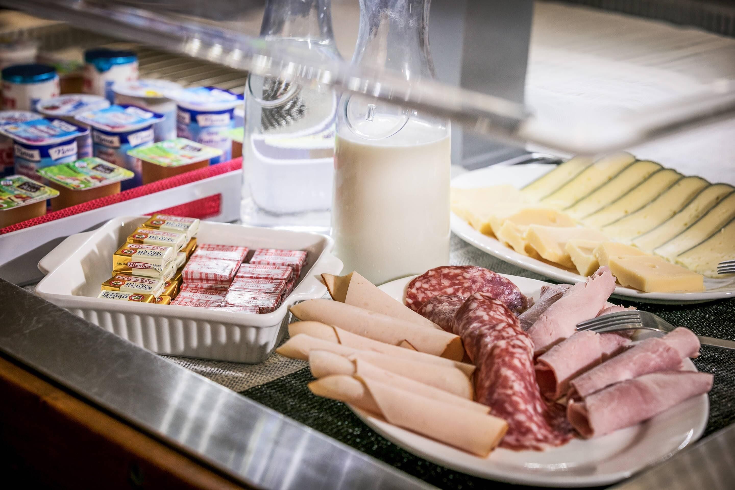 On trouve sur un comptoir une variété de produits alimentaires, notamment des fromages, des charcuteries et des produits emballés.