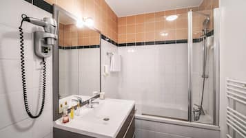 A modern bathroom with a hairdryer, sink, mirror, and a glass-enclosed shower area.