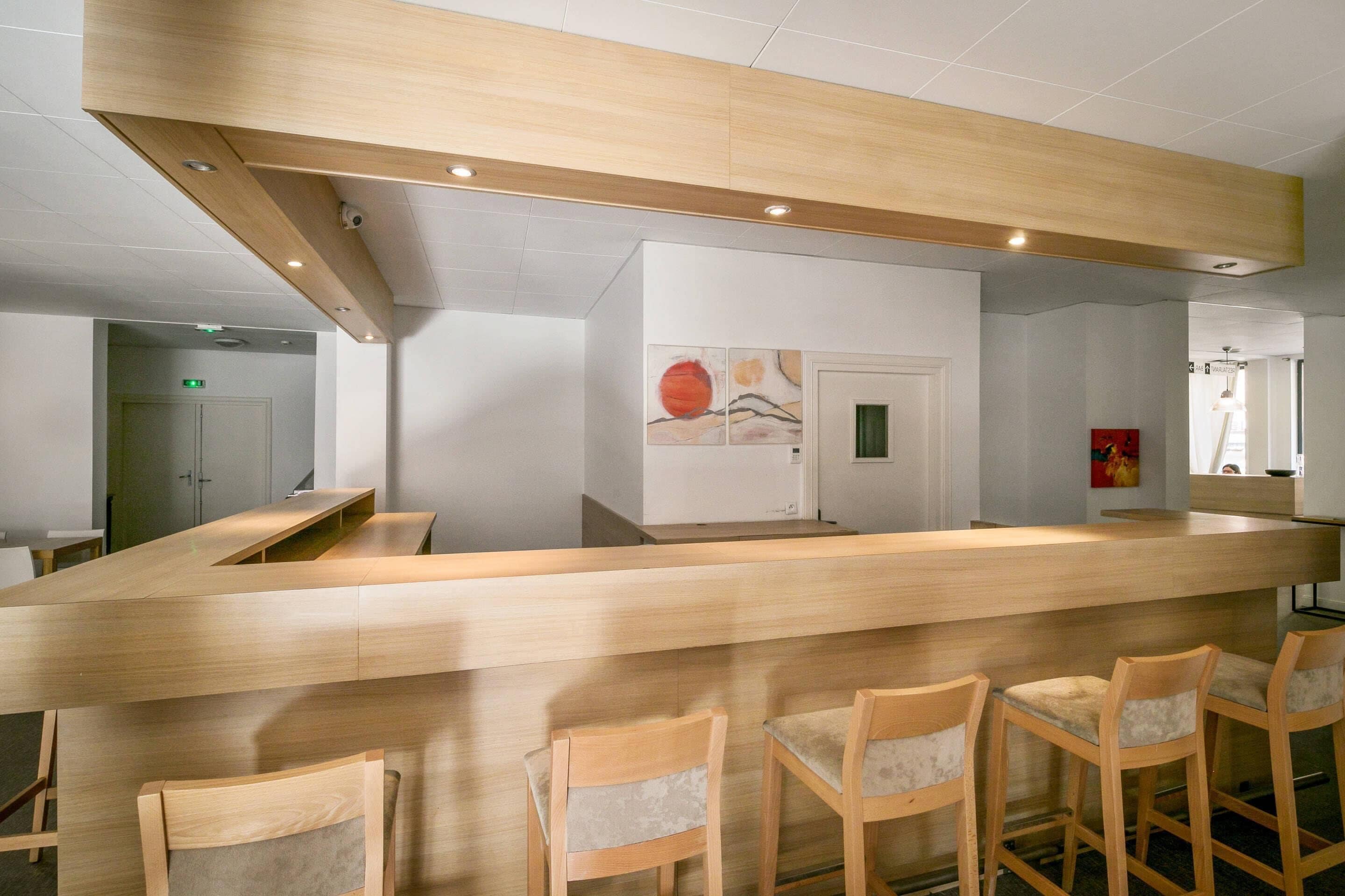A reception area with a wooden counter and bar stools.