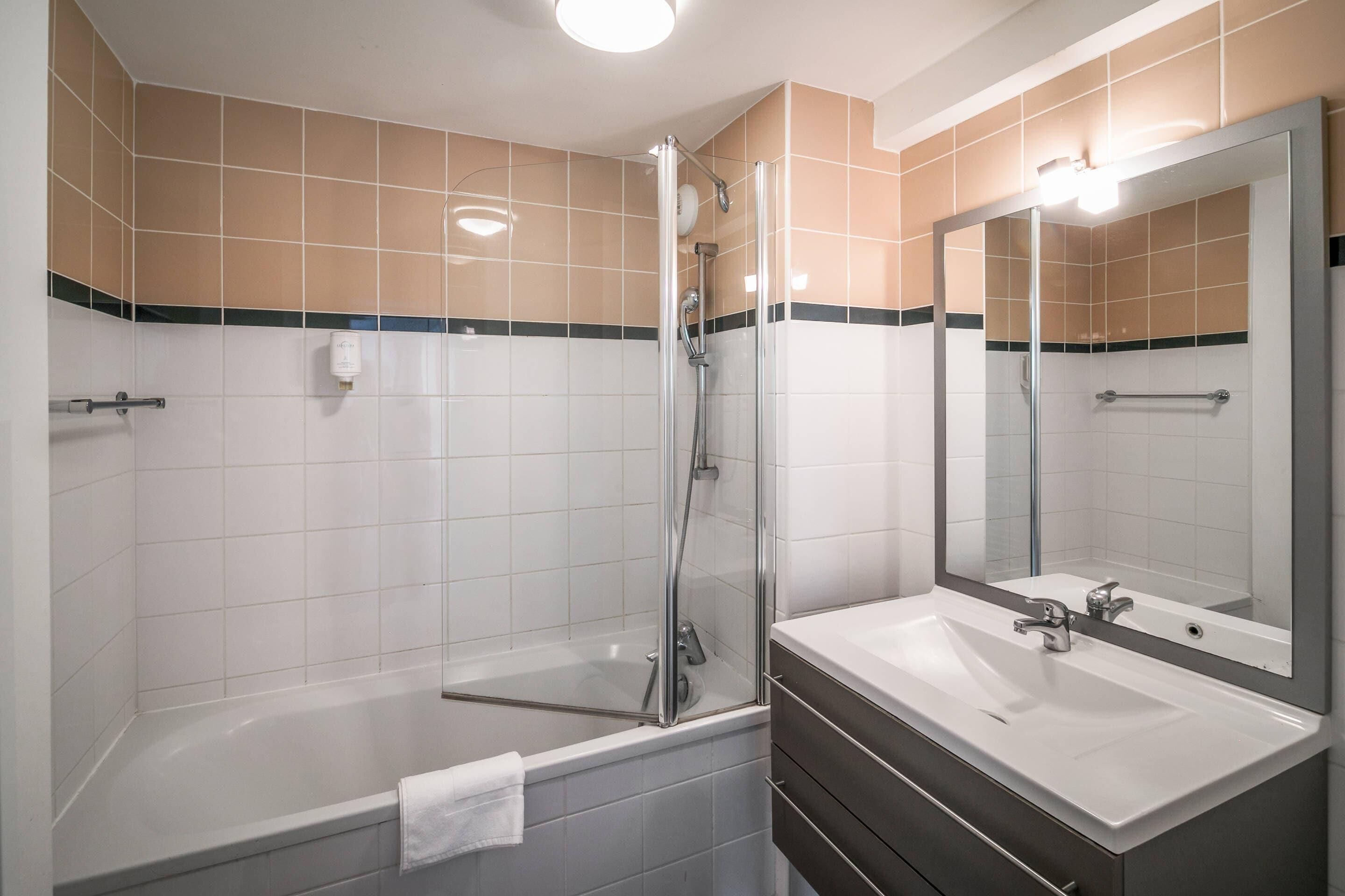 Un baño moderno con ducha envuelta en vidrio, un lavabo blanco y un espejo grande.