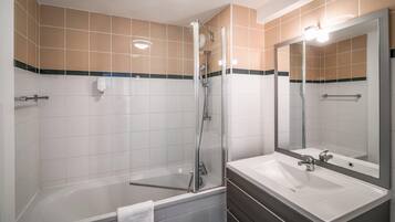Un baño moderno con ducha envuelta en vidrio, un lavabo blanco y un espejo grande.