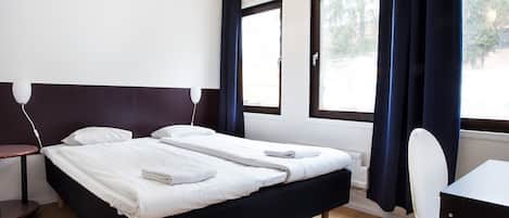 A hotel room with a bed, a desk, and a chair.