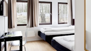 Ein Hotelzimmer mit zwei Betten, einem Schreibtisch, einem Stuhl und großen Fenstern mit Vorhängen.