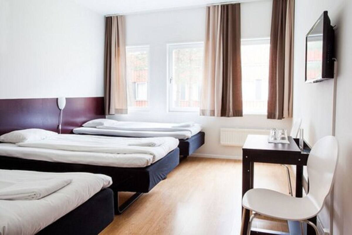 Ein Hotelzimmer mit zwei Betten, einem Schreibtisch und einem Stuhl.