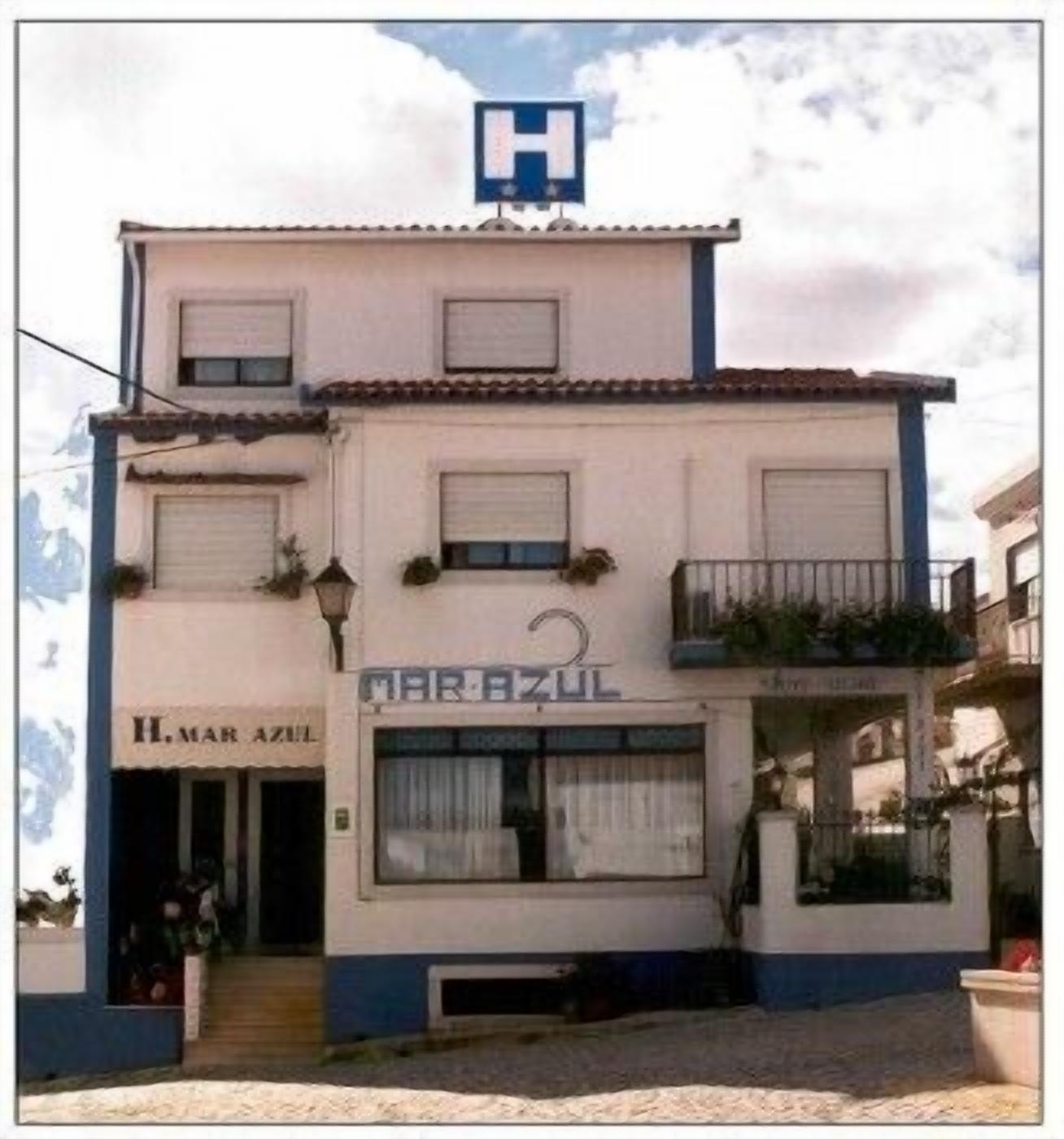 A two-story building with a sign reading "MARBEZUL" and a blue "H" on the roof, indicating a hospital.