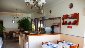 A dining area with a central island, chairs, and tables set with plates and cups.