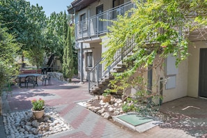 Une cour avec un patio, des sièges d’extérieur, un escalier et un pot de fleurs.