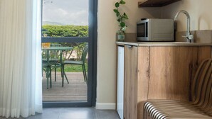 Una cocina moderna con microondas integrado, un armario de madera, un lavamanos y una silla.