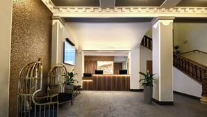 A reception area with a reception desk, two chairs, a large potted plant, and a staircase. - Hotel Europe Davos (Davos)