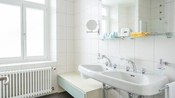 A modern bathroom with two sinks, a large mirror, and a window.