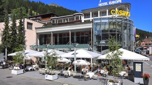A hotel with outdoor seating and a glass facade. - Hotel Europe Davos (Davos)
