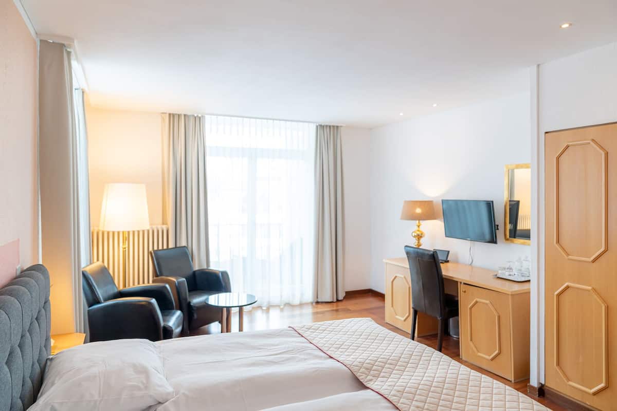 A hotel room with a bed, a desk, a chair, and a television.